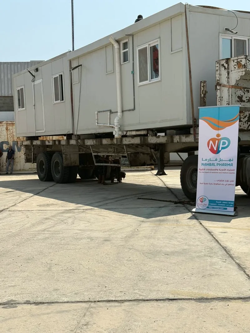 Mobile clinic unit exteriors on a transport trailer with a Nahbal Pharma banner in the foreground