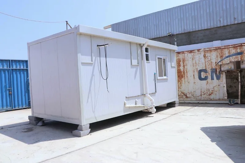 Rear exterior of a clinic unit with windows, pipes and visible external wiring