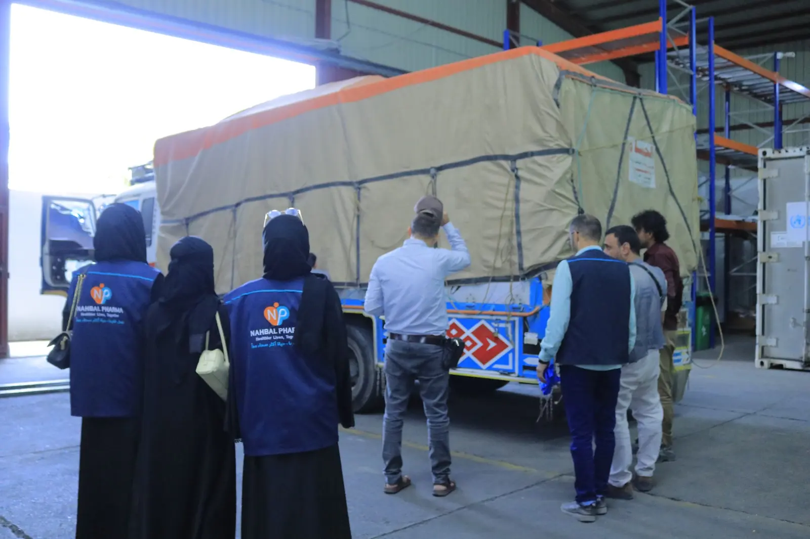 Nahbal team beside the shipment vehicle at the warehouse entrance